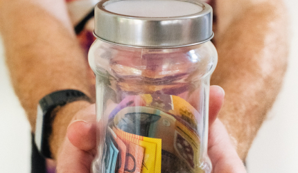 a person holding a jar with money in it